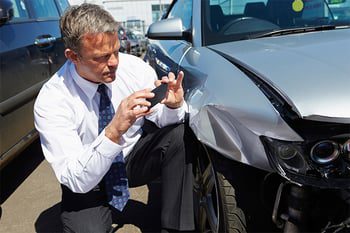 A man takes photos after a car accident