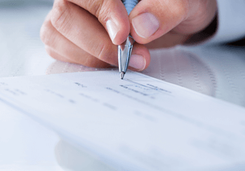 Hand signing a check to retain a personal injury lawyer