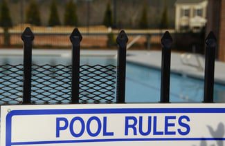 A sign reads pool rules to reduce liability