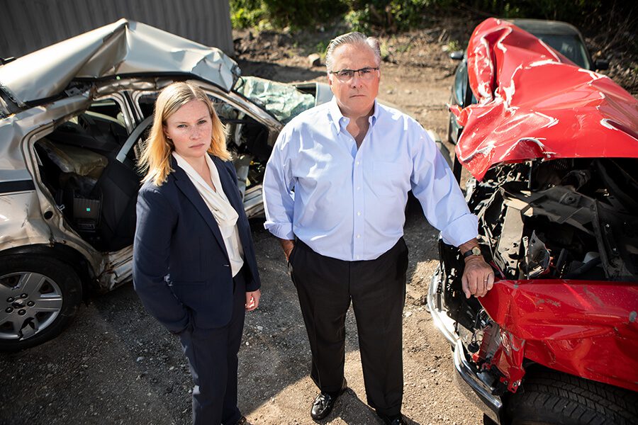 Milwaukee car accident lawyers in front of two crashed cars.